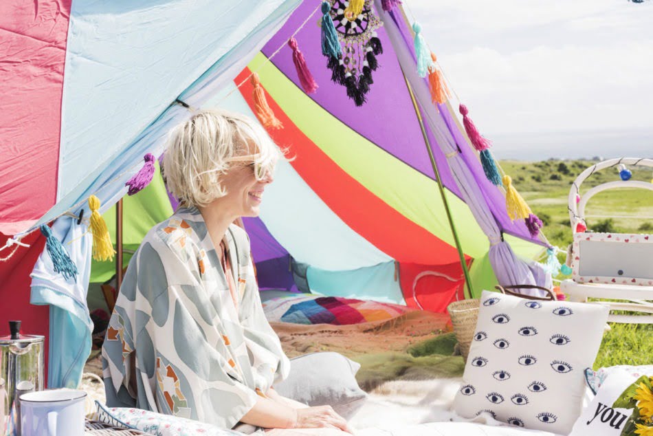 Maxine sitting outside of a fabric tent, enjoying the sun