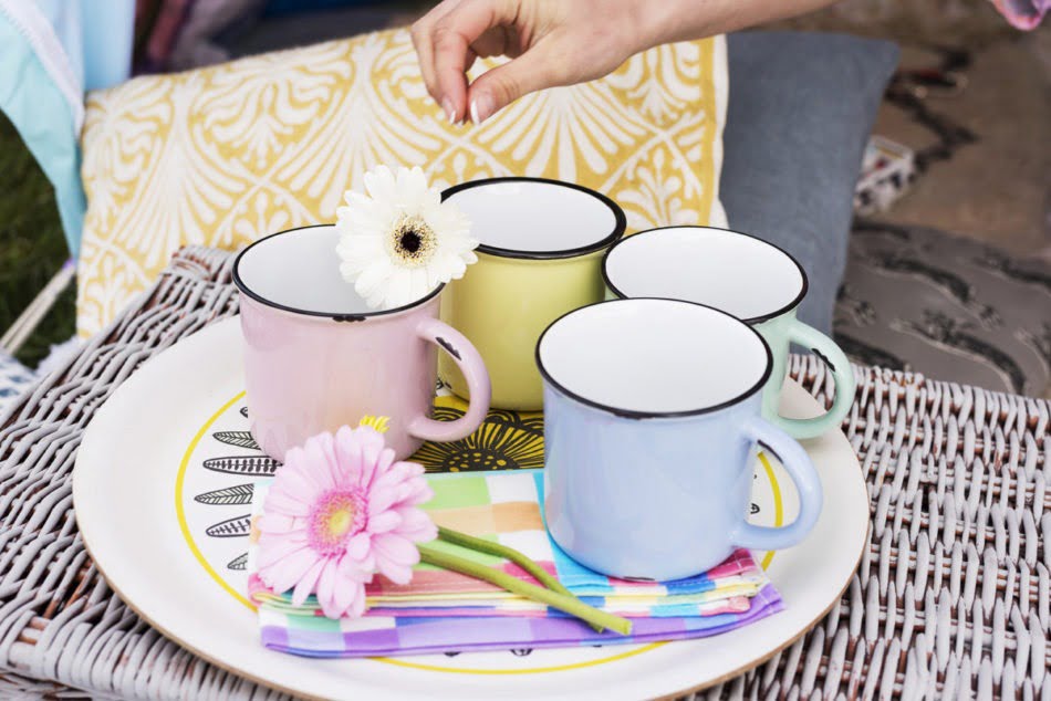 A flower being placed on top of some colourful mugs