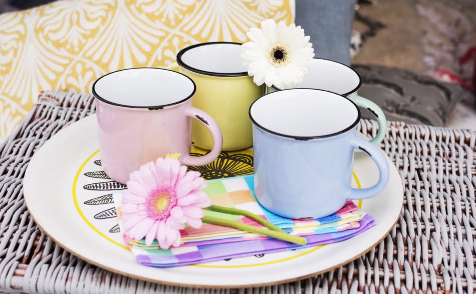 A flower resting on top of colourful mugs