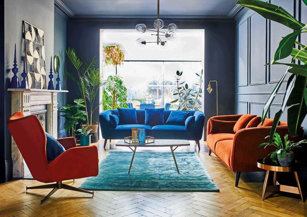 How to choose the perfect interior colour scheme for your home by interior stylist Maxine Brady from welovehomeblog.com
Navy blue living room with orange chairs and blue velvet sofa, herringbone flooring and mantlepiece 