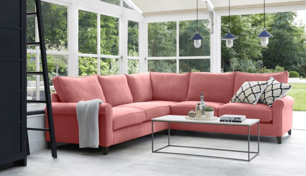 Discover these top 5 buyer's tips for buying a corner sofa by interior stylist and lifestyle blogger Maxine Brady from We Love Home Blog. pink corner sofa in fabric in conservatory / garden room / living room with lighting and coffee table.