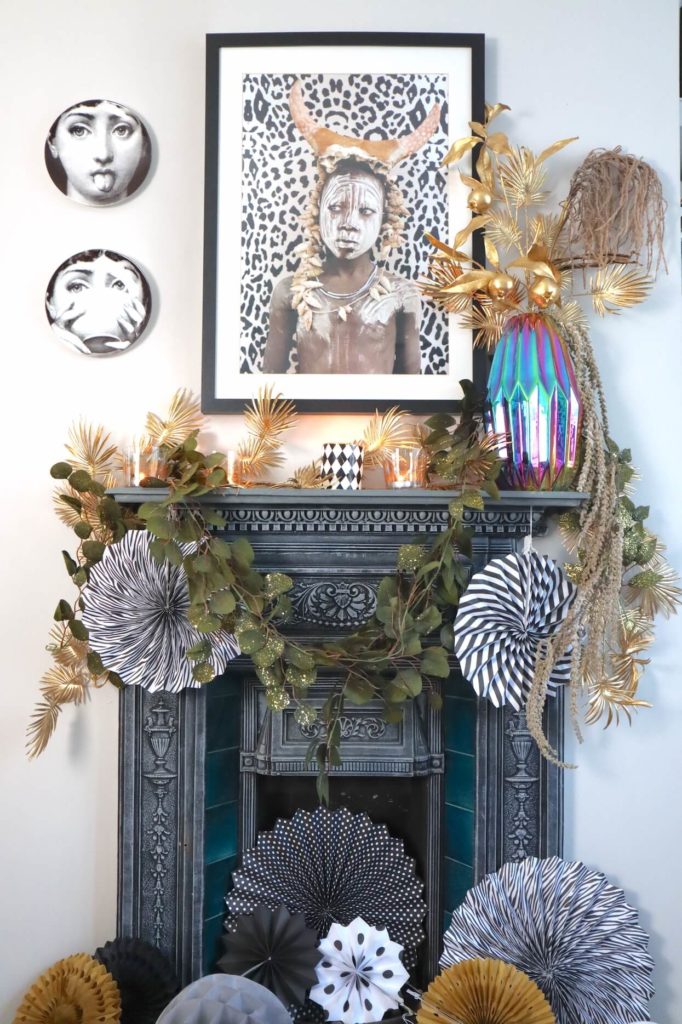 Fireplace & mantelpiece dressed with garland and paper decorations with cocktail gold trolley. black and white art. 7 cool Zoom Party Styling Ideas