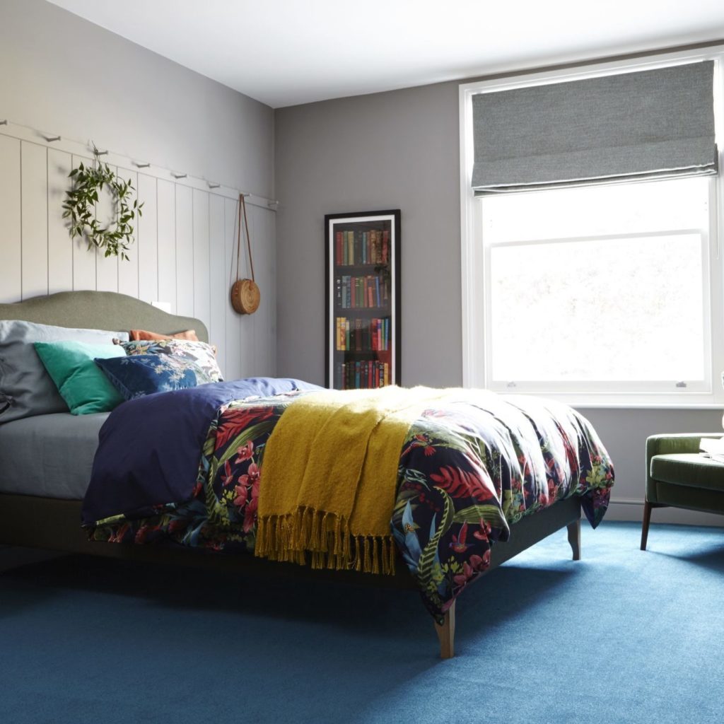 bedroom with blue carpet and painted panel wall, peg rail, green retro chair by Interior Stylist Maxine Brady
