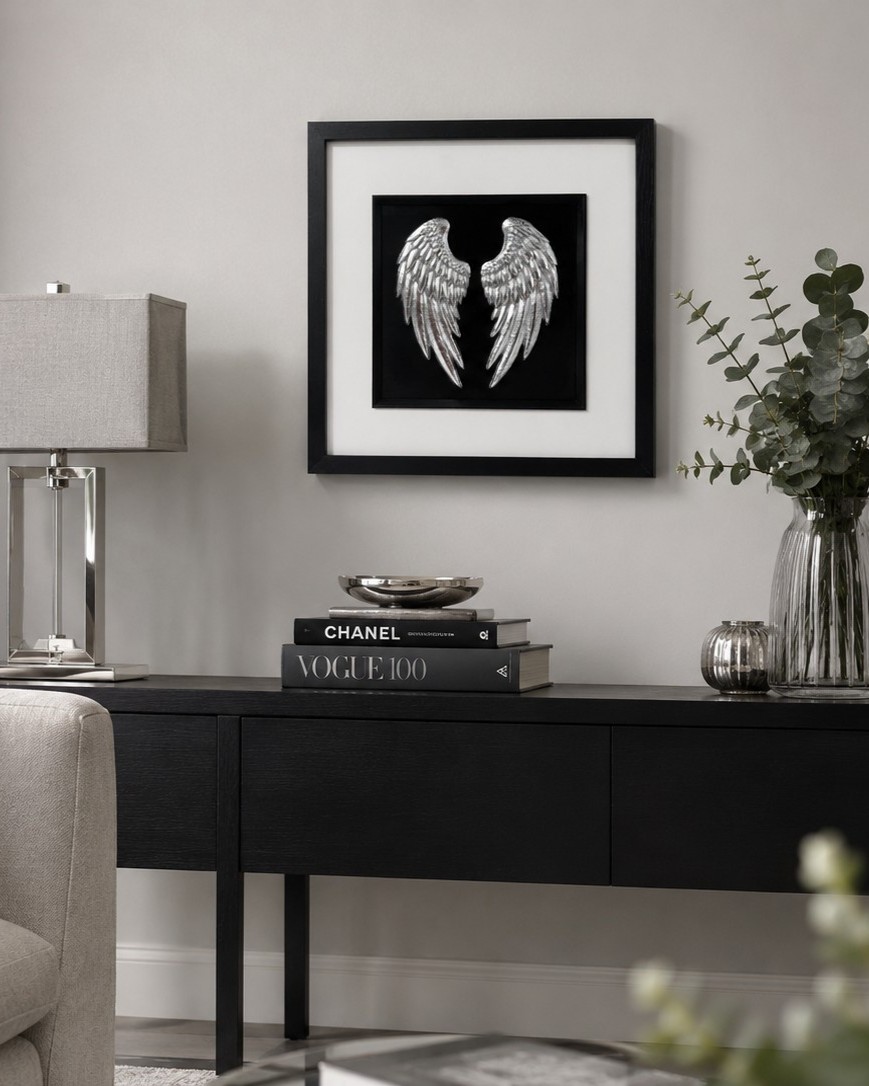 How to choose wall art for your home: Silver angel wings wall art in a black frame styled on a dark console table